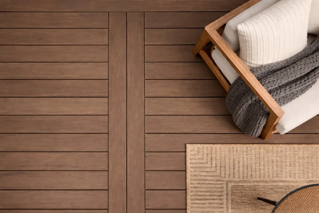 Top-down view of brown composite decking with outdoor lounge chair and woven rug